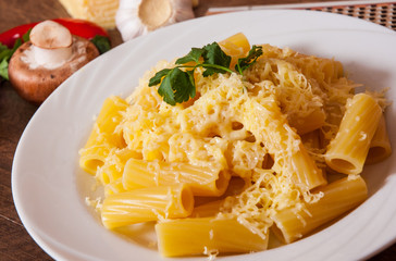 rigatoni pasta with cheese in a plate on wooden table