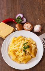 rigatoni pasta with cheese in a plate on wooden table