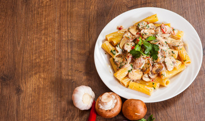 rigatoni pasta with mushroom sauce in a plate on wooden table
