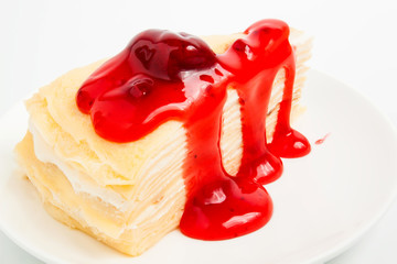 Vanilla crape cake on white dish with strawberry jam