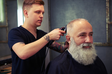 Barber making hear to handsome bearded man