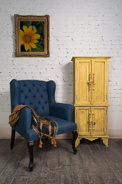 Composition of vintage blue armchair, yellow cupboard and framed painting