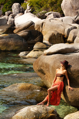 femme qui bronze sur un rocher au bord de l'eau