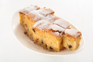 Homemade lemon cake with chocolate chips shot over white background from above. Full length view