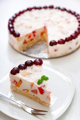 Cake with cherris, gelly yogurt and fruits. Isolated on white background. One piece in a white plate. Vertical shot