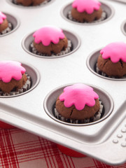 Glazed cupcakes with white and purple glazing on a baking tray