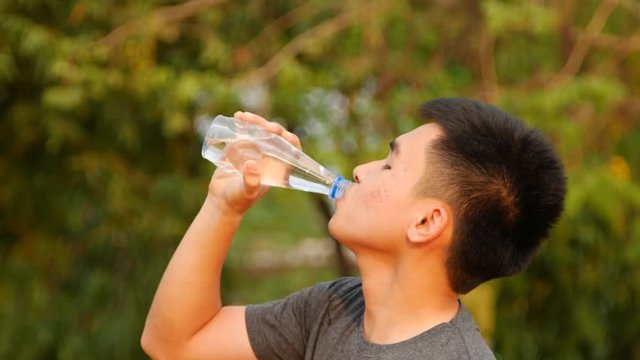 Close-up of a young man drinking water from a bottle outside