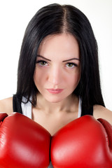 Portrait of a beautiful brunette girl in red boxing gloves.