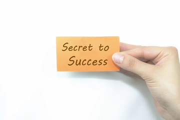 hand holding orange card written secret to success over isolated