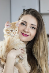 cute long-haired blonde young woman holding a cat smiling attractively vertical view