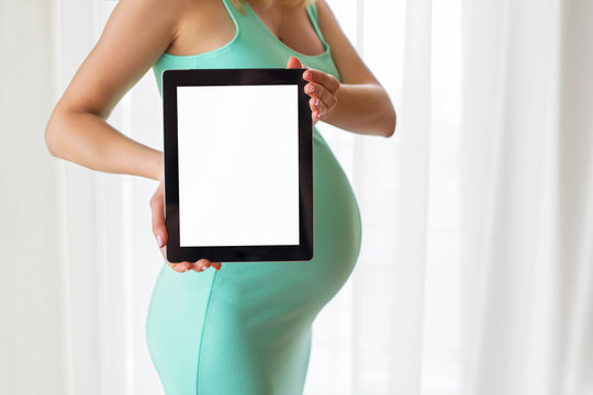 Pregnant woman holding blank screen tablet