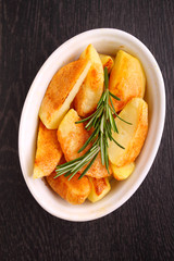 baked potatoes with spices in white bowl on a black background