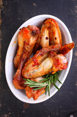 Chicken wings fried in tomato sauce, black background