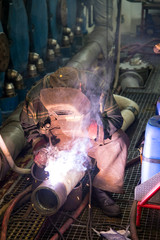 Welder during the repair welding of the pipeline in the engine room of the ship - obrazy, fototapety, plakaty