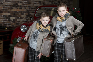 Fototapeta premium The boys in jackets and shorts with suitcases. Retro style. Red retro car