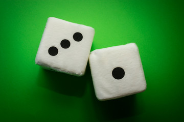 Pair of white plush dices on the green background