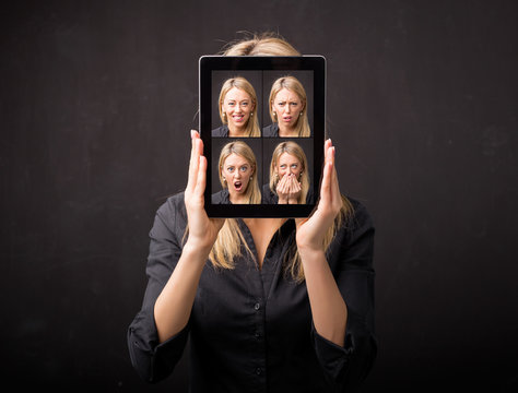 Woman holding tablet with different faces in front of her