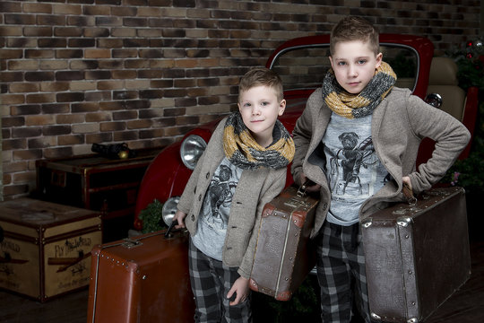 The boys in jackets and shorts with suitcases. Retro style. Red retro car