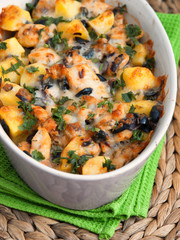 Casserole dish with potatoes, chicken breasts, olives and fresh herbs. Vertical shot