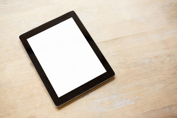 Tablet with empty white screen on wooden table
