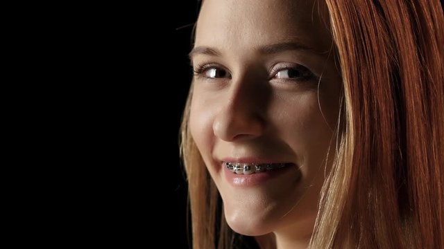 Girl with braces turns to the camera and smiling. Black