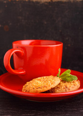 Fototapeta na wymiar red cup with tea and cookies on a black background