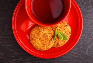 red cup with tea and cookies on a black background