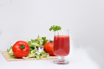 tomato juice in a glass with tomatoes and greens