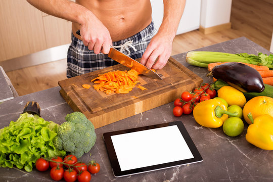 Man In Kitchen Using Tablet For Cooking Recipe