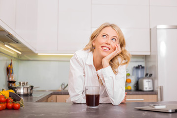 Woman in the kitchen with coffee daydreaming