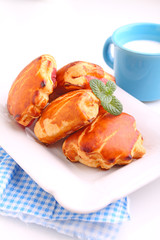 cheese buns with cherry jam. Blue cup with milk. White background.