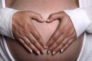Poster zwangere vrouw houdt beide handen in hartvorm op haar buik © Carmela