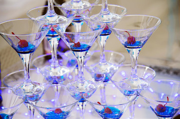 Pyramid from champagne glasses with cherries. Festive alcohol. Alcohol at the party.