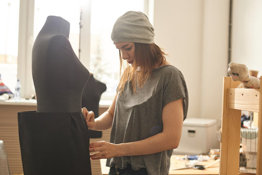 Seamstress in the process of fitting the skirt on the mannequin in the Studio