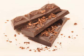 Pieces from a chocolate bar and chocolate crumbs on a white back