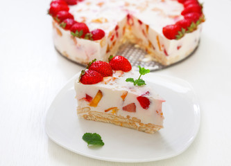 Cake with strawberries, gelly yogurt and cherries shot from above. Isolated on white background. One piece in a white plate