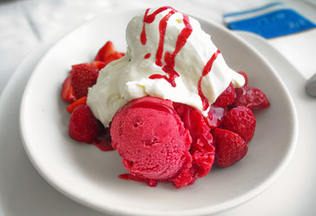 Strawberries with vanilla and fruit ice cream on a white plate