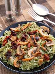 Italian Linguini pasta with pesto and mushrooms in a dark plate. Vertical shot