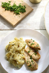 Grilled chicken fillets marinated in lemon juice and olive oil, with mashed potatoes cooked with sour cream and parsley. More parsley on the side. Top view. 