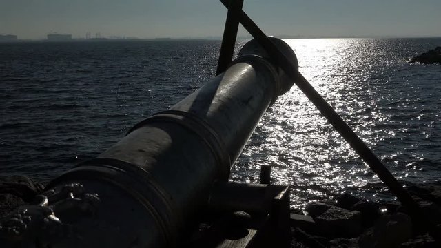 Ship gun barrel looks towards the sea standing on a recoil device on the coast