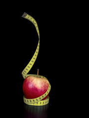 Apple and tape measure on black. Healthy eating, weight concept.