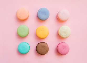Sweet colorful French macaroon biscuits on pastel pink background
