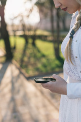 girl with smartphone outdoors in park. Closeup of female hands a
