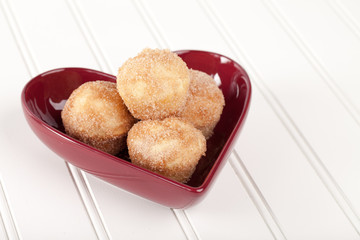 Macro shot of a heart shaped bowl filled with mini French breakfast puffs homemade