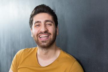Smiling casual man close up portrait against dark background.