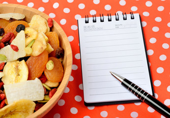 Bowl with dried fruits and notebook