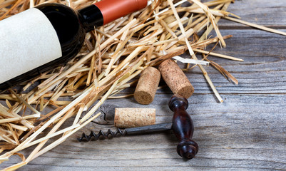 Vintage wine corkscrew with bottle of red wine on straw 