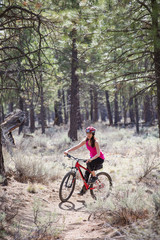 Fototapeta premium Woman riding mountain bike on trail in forest