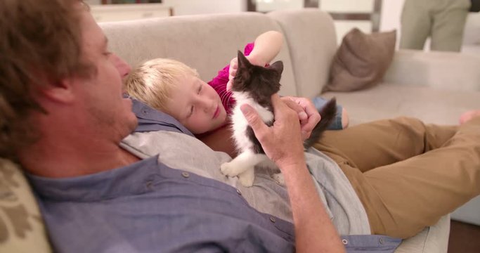 Modern Dad Holding Cat for Son to Pet on Couch