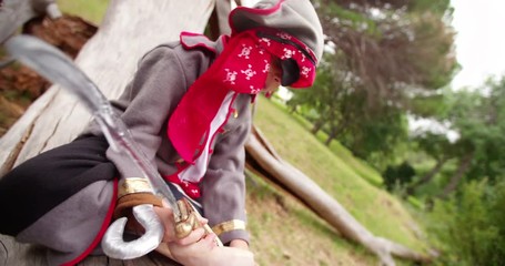 Boy dressing up as pirate sitting on log reading map